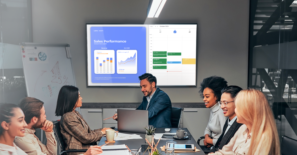 Coworkers in a meeting and a digital signage screen showcasing data